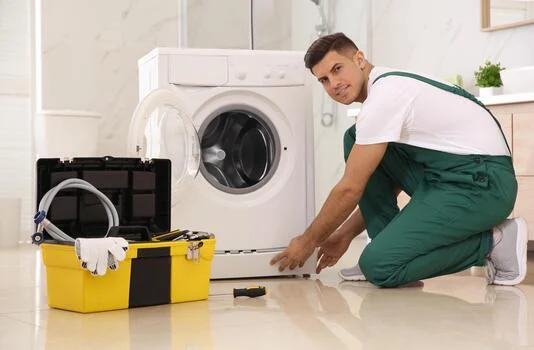 Technician beside a front-loading washing machine with a yellow tool kit